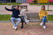 © JoseIMartin - A couple is sitting on a bench taking a self-portrait with their cell phone while an angry girl looks at them. She is envious