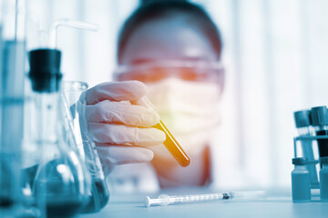 A laboratory researcher is holding a test tube of blood samples to view the results of the virus detection. To show positive results, the concept of a COVID 19 virus detection