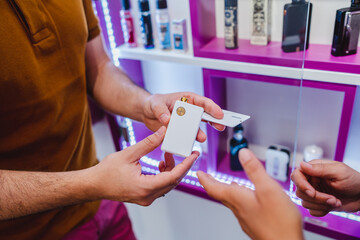 closeup shot of seller and client's hands holding an electronic cigarette