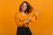 © Look! - Front view of happy girl isolated on yellow background. Studio shot of blissful brunette woman in elegant blouse.