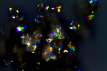 Wall Mural - shiny glimmer abstract on black background, made with a jewel out of focus.