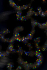 Wall Mural - shiny glimmer abstract on black background, made with a jewel out of focus.