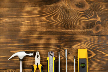 Top view of yellow construction instruments and tools on wooden DIY workbench with copy space at center.