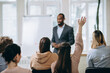 © master1305 - Focus on student. Male speaker giving presentation in hall at university workshop. Audience or conference hall. Rear view of unrecognized participants. Scientific, business event, training. Education