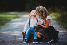 Adorable Children Siting On A Vintage Suitcase Throwing A Kiss