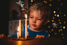 Beautiful Young Child Looking At Candles At Home During Christmas