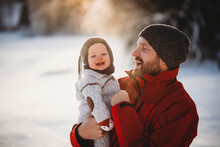 Father Holding Beautiful Smiling Baby Outside In Snow In Scandinavia