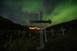 © Cavan Images - Northern Lights - Aurora Borealis shine in sky over wooden crosses of Tasiilaq cemetery, Greenland