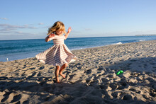Little Girl Dancing On The Beach With Blue Skies