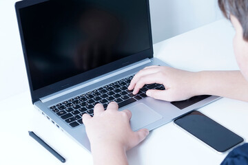 boy using a mobile phone and laptop at his desk.