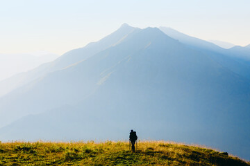silhouette of a lonely traveler at sunrise on the background of a high mountain
