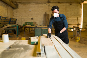 Sticker - Handsome worker using a table saw to cut wood boards