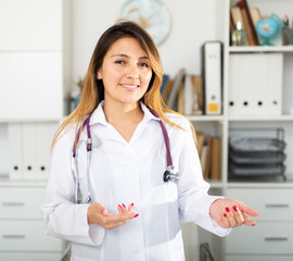 Wall Mural - Young mexican female medic in uniform standing in doctor's office