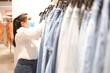 © TECHNOLOGY FACTORY - Asian women wear surgical mask choose jeans in department store new normol to covid-19 coronavirus 2021