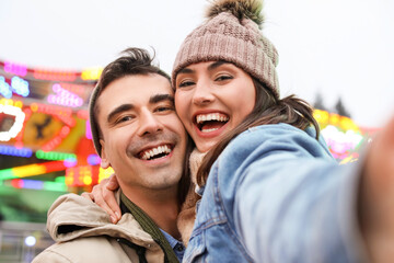 Canvas Print - Happy young couple taking selfie in amusement park on Christmas eve