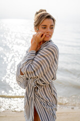 Summer closeup portrait of young positive woman in beautiful blue and white dress having fun on the sea. Romantic girl in bohemian outfit and tattoos smiling. Indie style, summer vacations.
