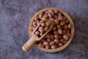 Wall Mural - Raw Groundnuts in the wooden bowl and the wooden scoop on cement background. Top view. 