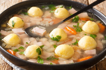 Wall Mural - Delicious Liechtenstein cuisine soup with ham and cornmeal dumplings close-up in a plate on the table. horizontal