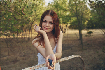 Wall Mural - pretty woman with a bunch of grapes in her hand stands near the iron bed cropped view trees nature autumn