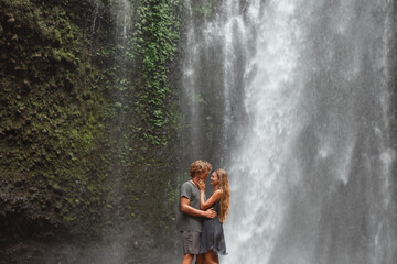 Wall Mural - Young traveling couple explore waterfall in Bali, love story, people in love, vacation in Asia