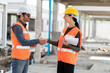 © supAVADEE BUTRADEE - A male engineer and a female institute wearing an accident prevention helmet and shaking their hands are willing to work together in a construction project.