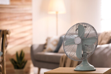 Poster - Modern electric fan on wooden table in living room. Space for text