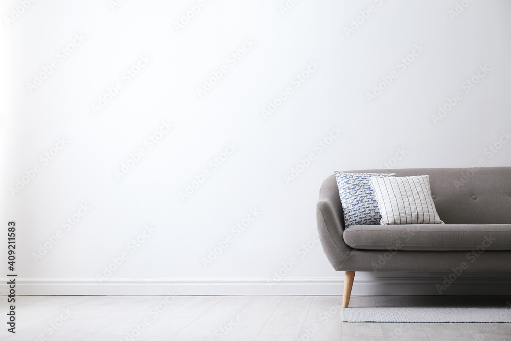 Obraz na płótnie Grey sofa with pillows near white wall in stylish living room interior. Space for text w salonie