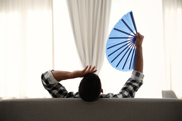 Poster - Man with hand fan on sofa. Summer season