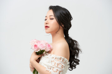 Beautiful young bride in wedding dress holding bouquet over white background. Copy space.