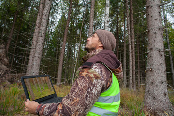 Wall Mural - Forest engineer works in the forest with a computer. Digital technologies in forestry. Computer forest inventory.