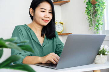 Wall Mural - happy Asian business woman working remotely from home office hand typing on computer laptop