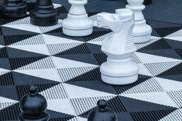 a sports chess game with different, large pieces standing on the ground
