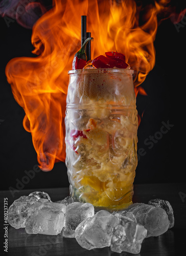 cocktail mango chili in glass on black background with ice and fire