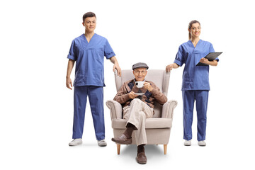 Male and female nurse standing next to an elderly man in an armchair