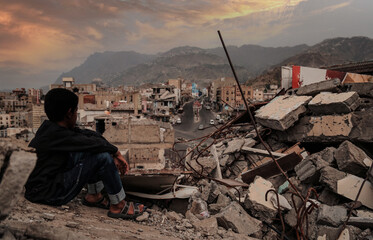 a child from taiz city sits on the ruins of his ruined home because of the war on city-yemen.
