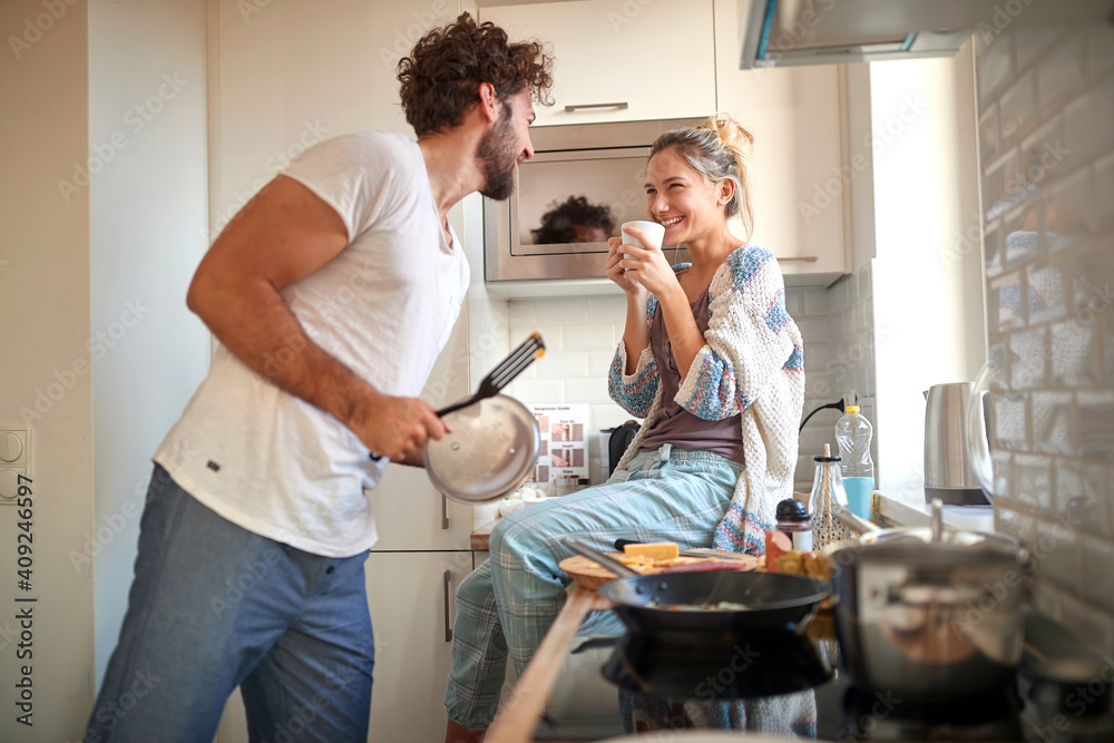 A young couple in love having good time while preparing a breakfast together. Cooking, together, kitchen, relationship - obrazy, fototapety, plakaty 
