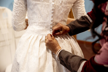 Poster - Closeup of someone closing the buttons of the bride's beautiful dress