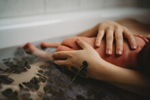 Close Up Of Mom's Hands Holding Newborn In Bath Tub After Birth