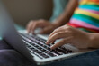 © Cavan Images - Close up of bi-racial tween girl's hands working on laptop