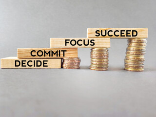 Wall Mural - Motivational and Inspirational Concept - Decide commit focus succeed text on wooden blocks with coins background. Stock photo.