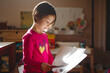 © Cavan Images - A little girl in beautiful light reads from sheets of paper