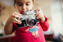 Little Girl Holding And Setting Analog Camera.