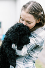 Woman Holding Her Black New Cute Poodle Puppy In Arms Lovingly