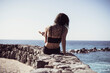 © Cavan Images - fit woman with tree tattoo sits by edge of ocean with cute dog on lap