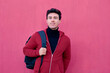 © Cavan Images - Handsome student man poses with a backpack on a pink background