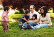 © Cavan Images - Familiy sitting in the grass in park