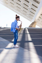 Woman With Ponytail Playing A Saxophone While Standing Outdoors