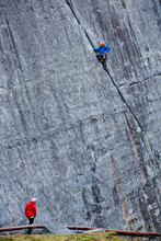 Man Climbing Up Steep Rock Face At Slate Quarry In North Wales