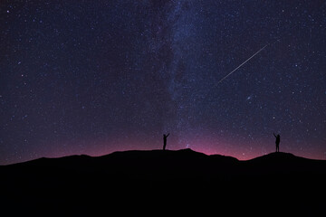 Wall Mural - beautiful starry sky with milky way galaxy. night landscape. two silhouettes stands on the hill and 