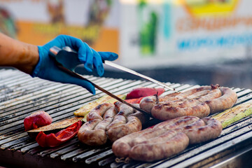 Wall Mural - Cook turns over the grilled sausage and vegetables. Street food. BBQ picnic